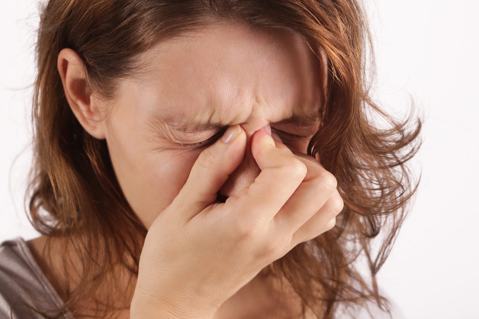 Woman pinching the bridge of her nose from sinus pressure